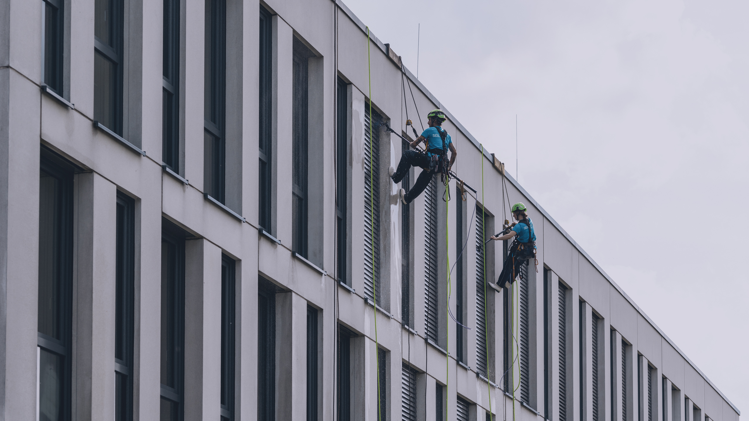 Zwei Wandkletterer reinigen Fenster mit Osmose-Technologie